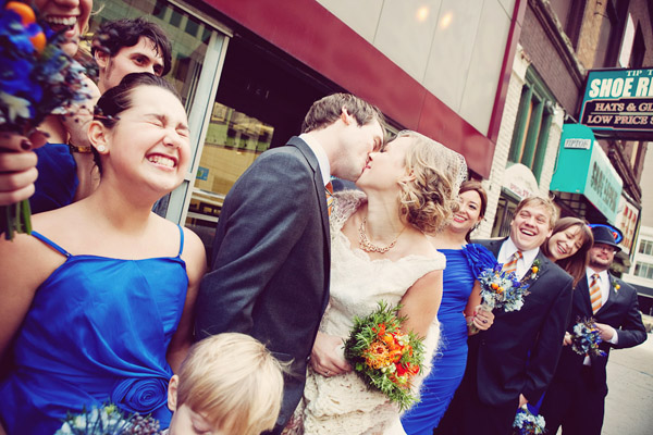 Adorable wedding photo by Abby Rose Photography of couple kissing surrounded by wedding party.